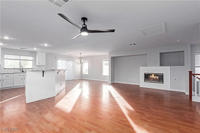 kitchen with open floor plan, light wood finished floors, a kitchen island, and white cabinets