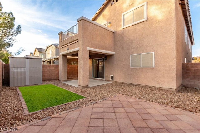 back of house featuring a patio area, an outdoor structure, a fenced backyard, and stucco siding