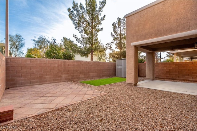 view of yard featuring a fenced backyard, an outbuilding, and a patio