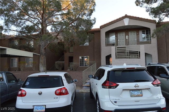 view of front of property with a tile roof, stairway, and stucco siding