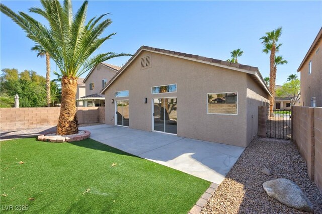 rear view of house with a patio area, a fenced backyard, a lawn, and stucco siding