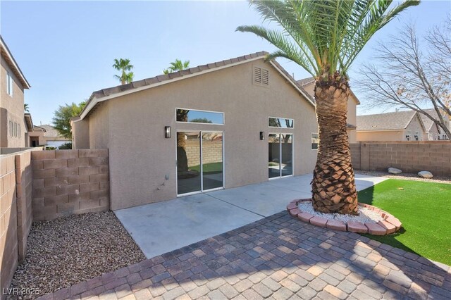 rear view of house featuring fence, a patio, and stucco siding