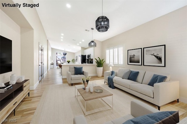 living area featuring lofted ceiling, baseboards, light wood finished floors, and recessed lighting