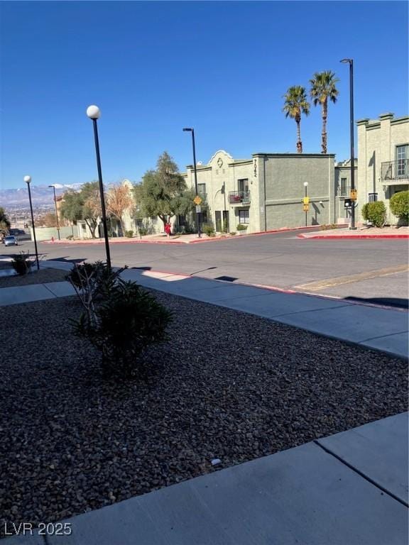 view of road featuring street lights, curbs, and sidewalks