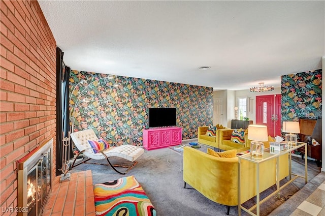 carpeted living room with a textured ceiling, a fireplace, visible vents, and wallpapered walls