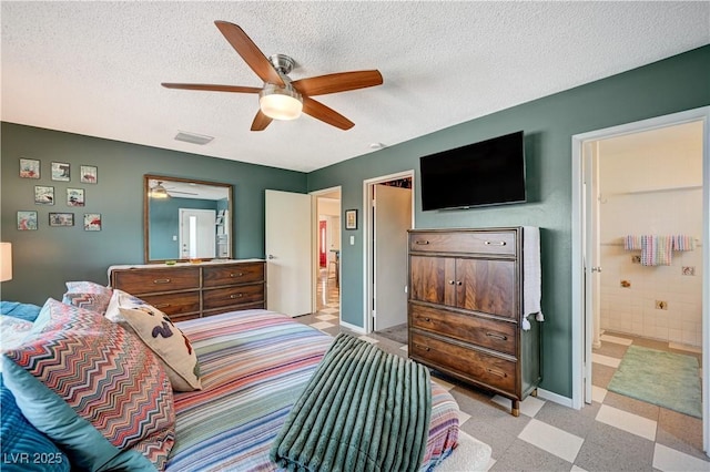 bedroom with light floors, visible vents, a textured ceiling, ensuite bath, and baseboards