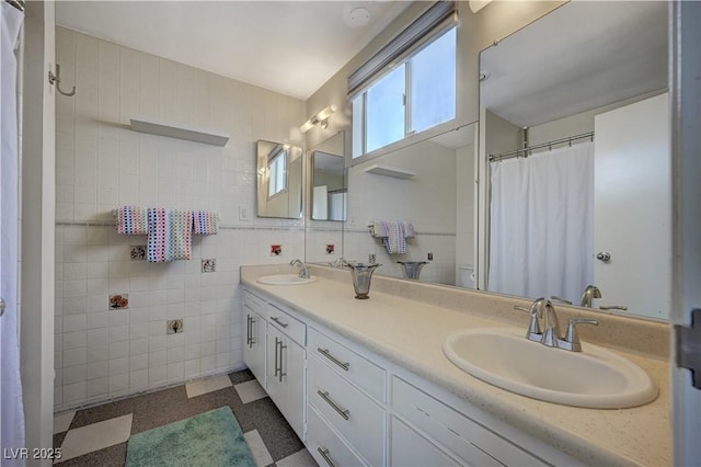 bathroom with double vanity, a sink, tile walls, and tile patterned floors