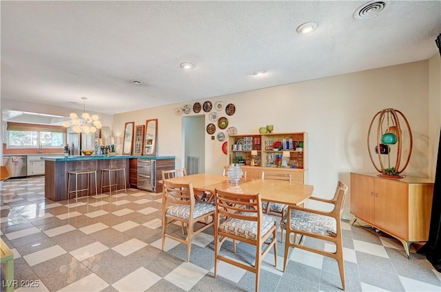 dining space with light floors, a textured ceiling, visible vents, and a notable chandelier