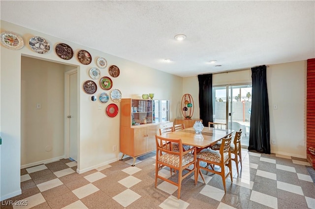 dining space featuring light floors, baseboards, and a textured ceiling