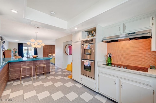 kitchen with light floors, black electric stovetop, tasteful backsplash, stainless steel double oven, and under cabinet range hood