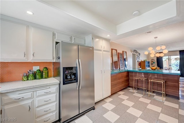 kitchen with light floors, white cabinets, a notable chandelier, and stainless steel fridge with ice dispenser