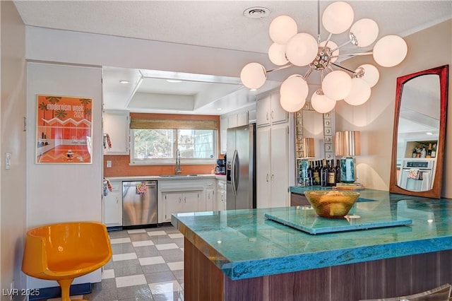 kitchen with light floors, white cabinetry, appliances with stainless steel finishes, and a sink