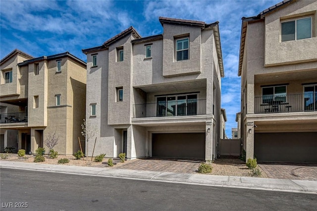 view of front of home featuring decorative driveway, an attached garage, and stucco siding