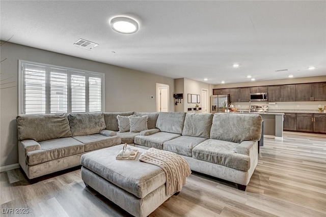 living room with baseboards, recessed lighting, visible vents, and light wood-style floors