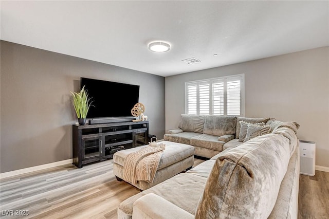 living room with baseboards, visible vents, and wood finished floors