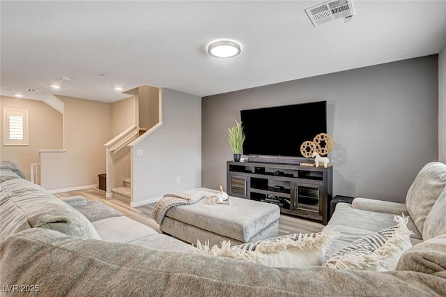 living room featuring wood finished floors, visible vents, baseboards, and stairs