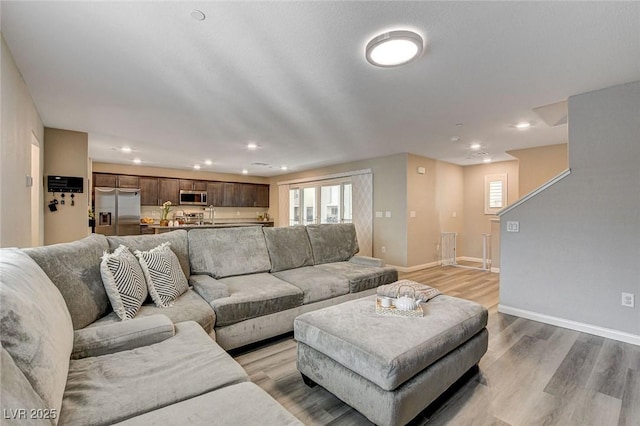 living area with light wood-style flooring, baseboards, and recessed lighting