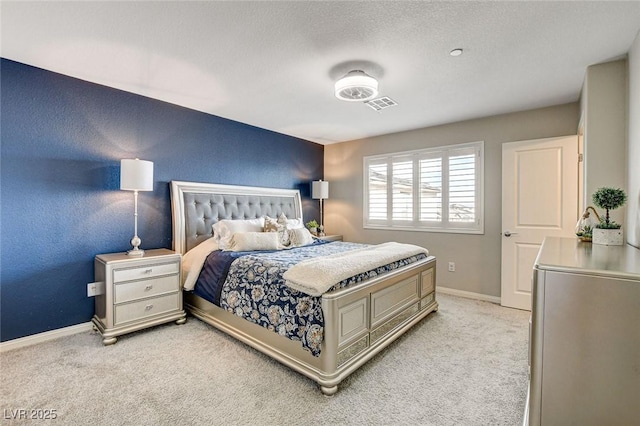 bedroom with light carpet, a textured wall, visible vents, and baseboards