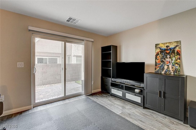 living area with light wood-type flooring, visible vents, and baseboards