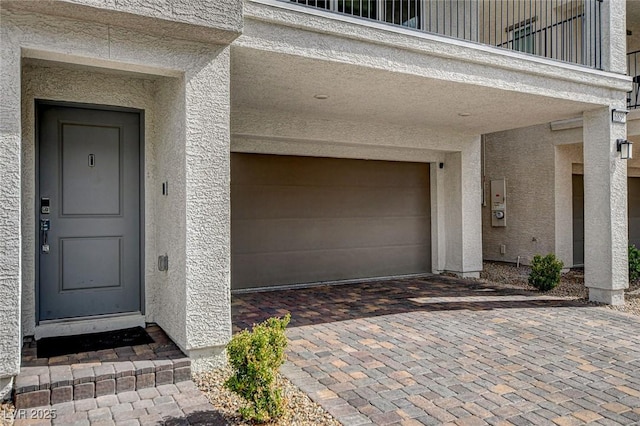 entrance to property featuring an attached garage and stucco siding