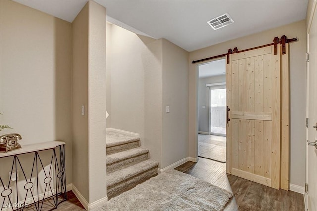 staircase with wood finished floors, visible vents, and baseboards