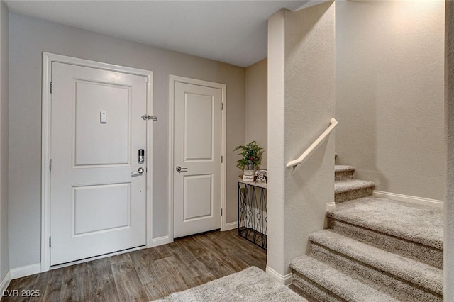 entrance foyer with stairs, wood finished floors, and baseboards