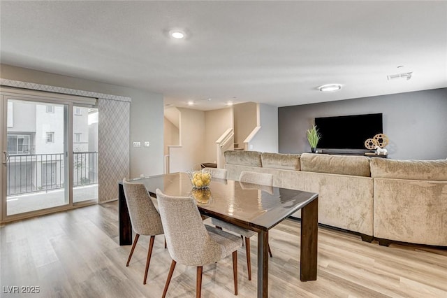 dining room with light wood-style floors, stairs, and visible vents