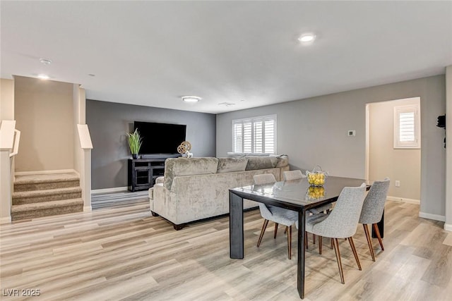 dining area featuring stairs, light wood-style flooring, and baseboards