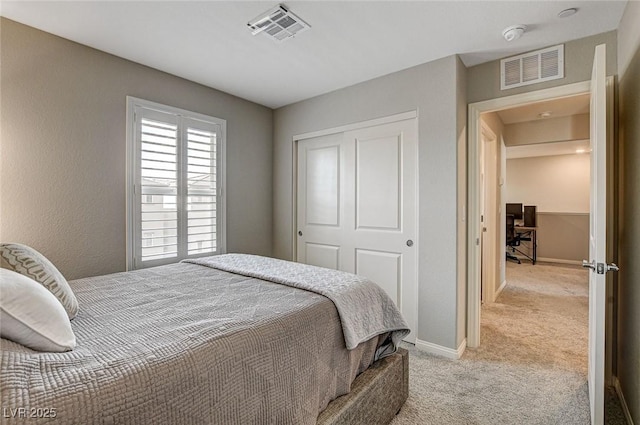 bedroom with light carpet, a closet, visible vents, and baseboards