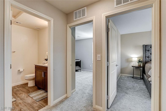 hall featuring light carpet and visible vents