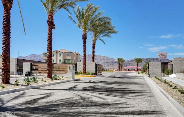 view of street with curbs, a gated entry, a gate, and a mountain view