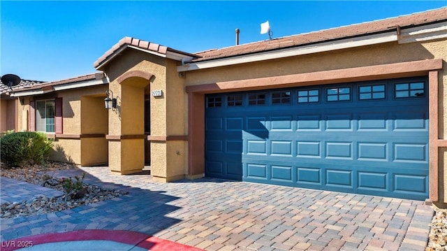 exterior space with a garage, decorative driveway, and stucco siding