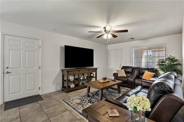 living area with a ceiling fan, light tile patterned flooring, and baseboards