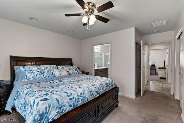 bedroom featuring light colored carpet, a ceiling fan, baseboards, visible vents, and ensuite bath