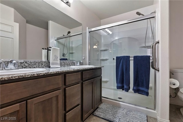 full bath with double vanity, a stall shower, a sink, and toilet