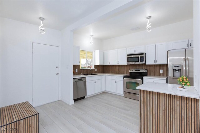 kitchen featuring light stone countertops, a sink, white cabinetry, and stainless steel appliances