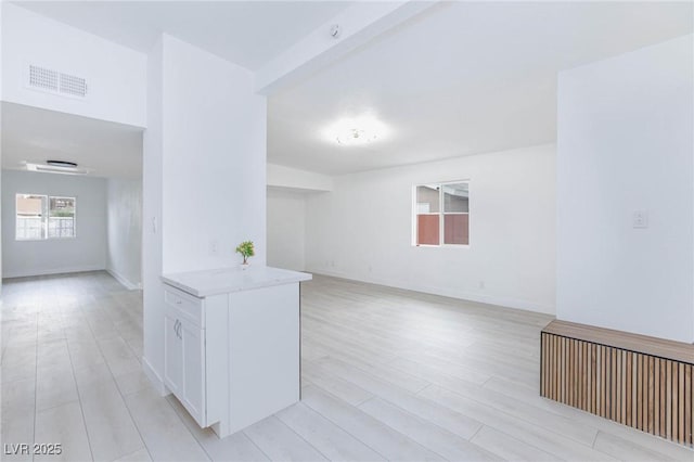 unfurnished room with light wood finished floors, visible vents, and baseboards