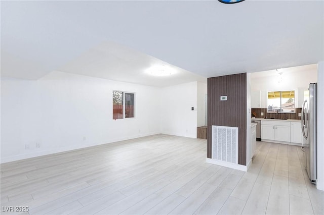 unfurnished living room featuring a sink, visible vents, and light wood-style floors