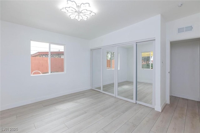 unfurnished bedroom with visible vents, light wood-style floors, and multiple windows