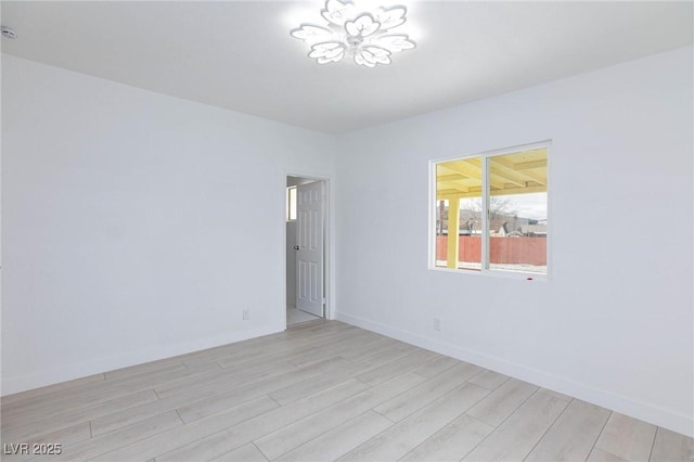 empty room featuring light wood finished floors and baseboards