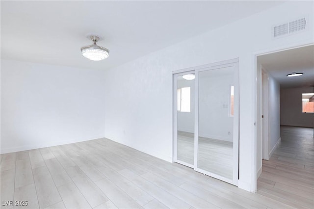 unfurnished room with visible vents, baseboards, and light wood-style floors