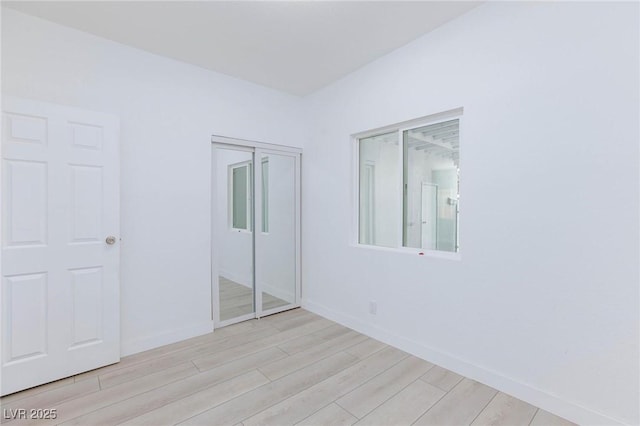 unfurnished bedroom featuring baseboards, a closet, and light wood finished floors
