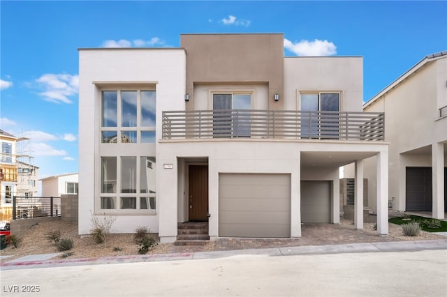 contemporary home featuring a balcony, driveway, an attached garage, and stucco siding