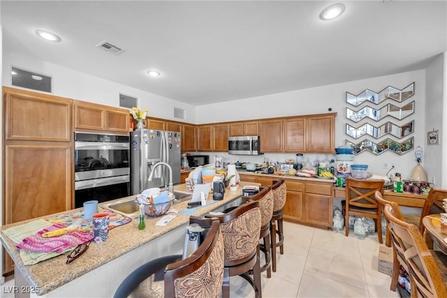 kitchen with a sink, visible vents, appliances with stainless steel finishes, and a breakfast bar area