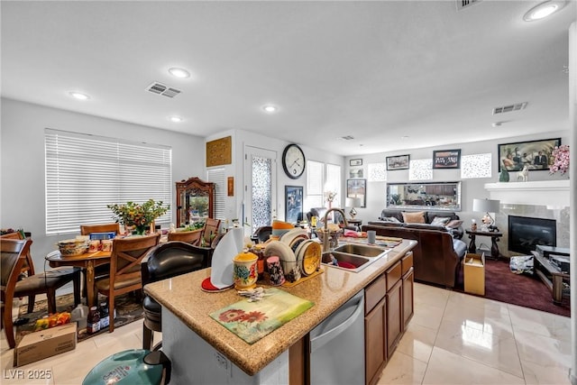 kitchen with dishwasher, a kitchen island with sink, a sink, and visible vents