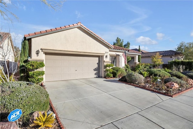 mediterranean / spanish-style home featuring concrete driveway, a tiled roof, an attached garage, and stucco siding