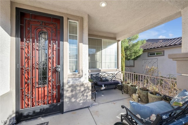 entrance to property featuring a porch and stucco siding