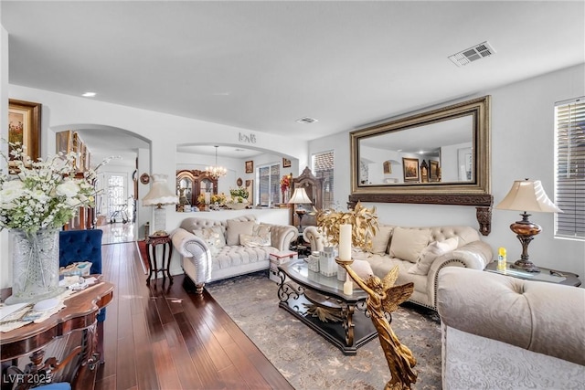 living room featuring visible vents, arched walkways, wood-type flooring, and a chandelier