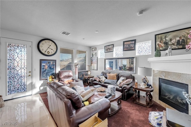 living room with tile patterned flooring, a glass covered fireplace, and visible vents