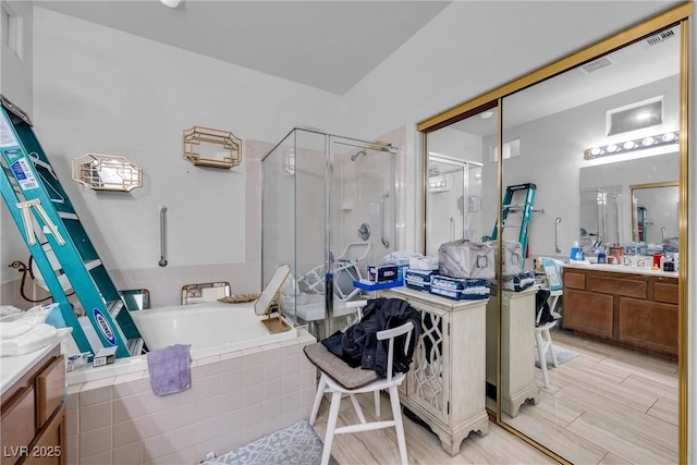 bathroom with visible vents, a stall shower, vanity, and tiled bath